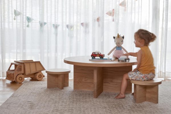 A child at a kids timber stool and table in a childs bedroom