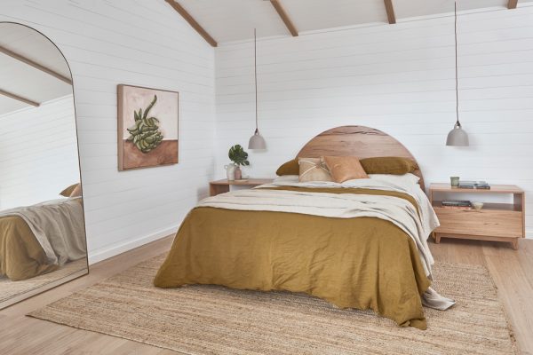 Curved timber bedhead with a styled bedroom setting.