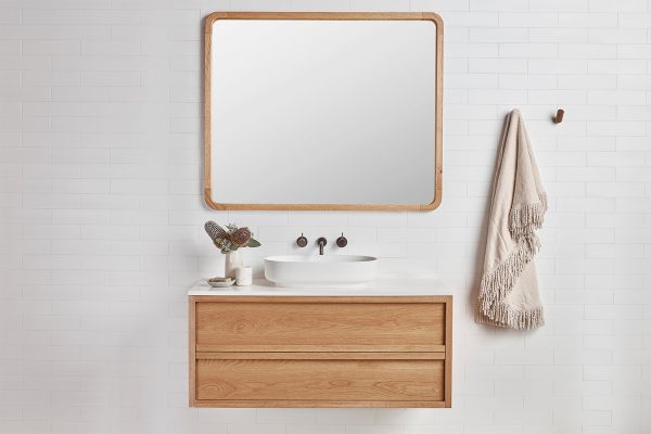 Timber frame mirror with curved edges over a single timber wall hung vanity