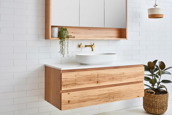 Mirrored bathroom cabinet with a storage shelf above a single sink floating timber vanity with two drawers. The timber vanity has a single sink with a stone bench top.