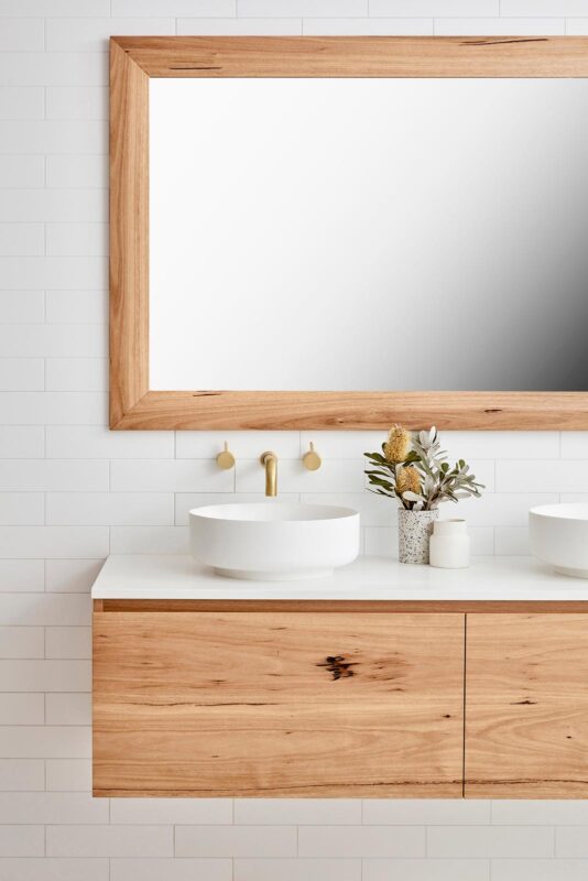 A timber vanity with two sinks under a timber framed bathroom mirror. Australian made and locally designed by Loughlin Furniture.