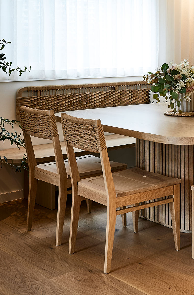 The Coogee Dining chair which is a timber chair with a weaved back is set at an Australian made timber dining table set in a coastal interior style dining room.
