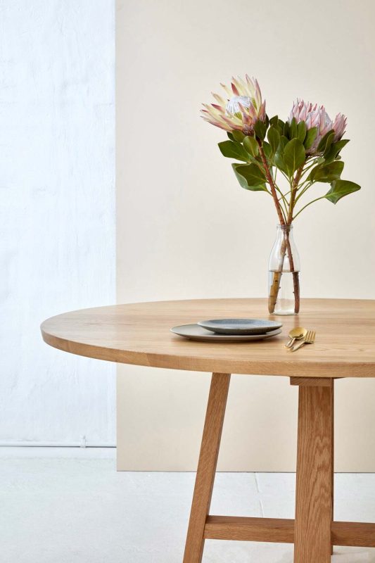 Loughlin Furniture Custom Designed Timber Table with a single place setting and 2 proteas in a vase.