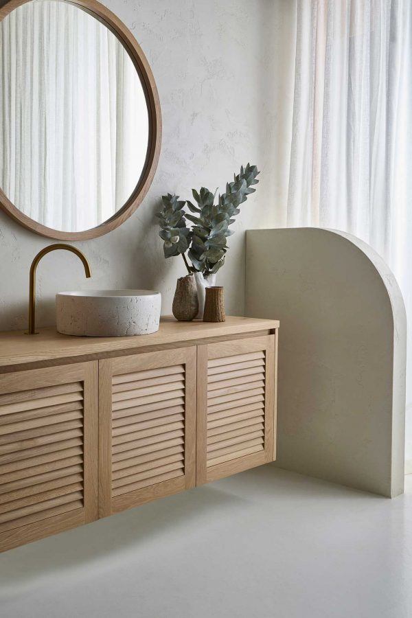 A modern coastal design bathroom with Loughlin Furniture custom vanity. This wall mounted timber vanity with a louvre door profile sits below a custom made round mirror.