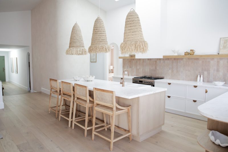 A modern light and bright kitchen. Shaker style white kitchen cabinets with a kitchen island and four timber high stools