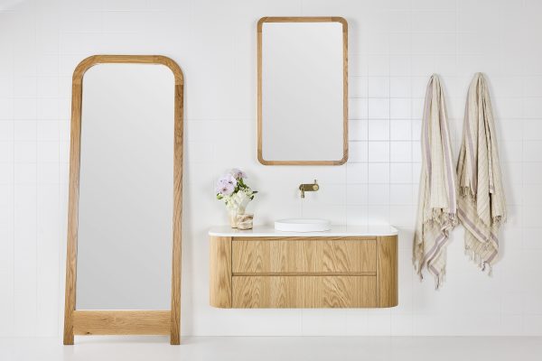 A full length mirror, a mirrored bathroom cabinet and a floating timber bathroom vanity styled in a modern coastal bathroom setting.