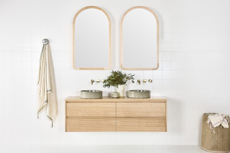 Staples floating bathroom cabinet under two arched timber framed mirrors